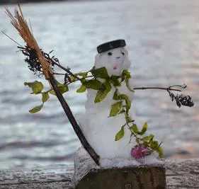 Snowman with leafy scarf by the water