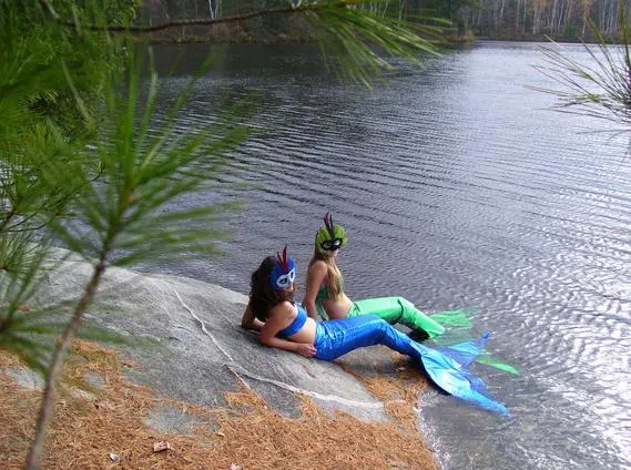 Two mermaids relaxing by a lake