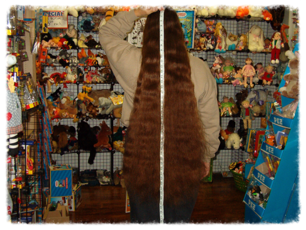 Person wearing a long, thick fur coat standing in a cluttered store.