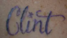 Clint" tattoo in cursive script