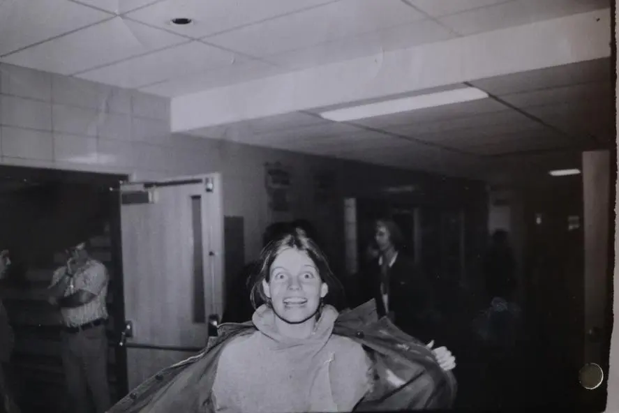 A smiling woman in a cozy sweater indoors, with a vintage atmosphere.