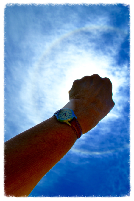 Fist raised toward a bright, cloudy blue sky.