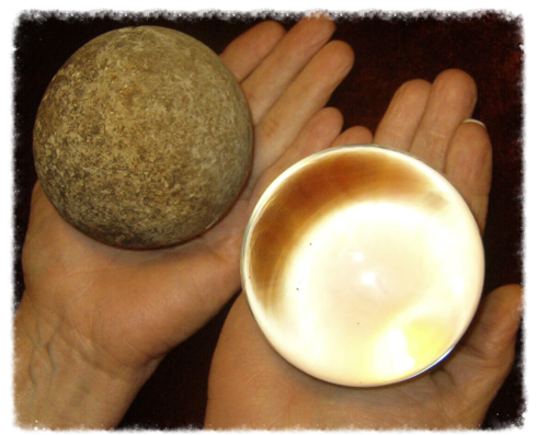 Two hands holding a round stone and a latte cup.