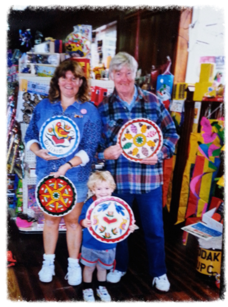 Family proudly displaying colorful handmade ceramic plates.