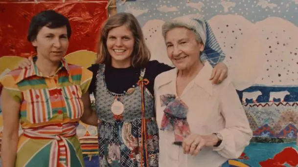 Three women smiling in front of mural