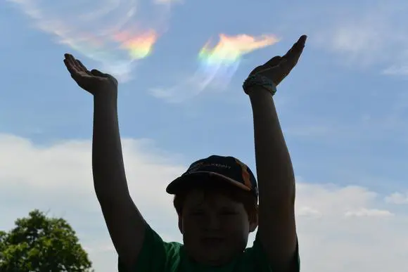 Silhouette of child with iridescent sky overhead